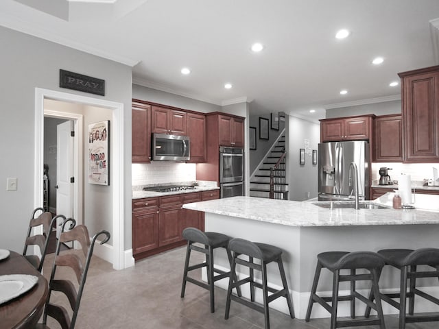 kitchen featuring stainless steel appliances, a breakfast bar area, a sink, and backsplash