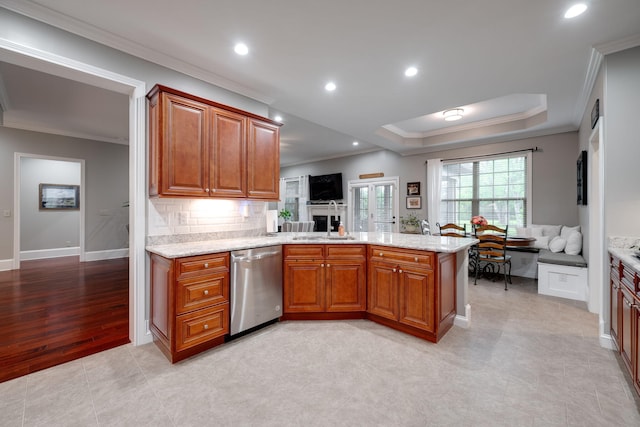 kitchen featuring stainless steel dishwasher, a peninsula, brown cabinets, and a sink