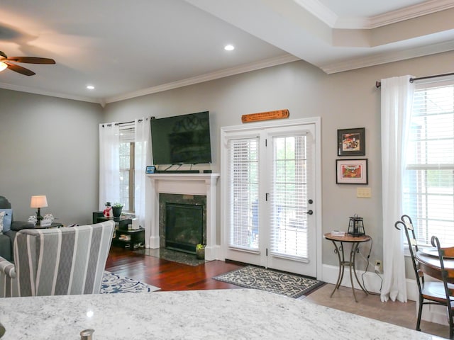 living area with a ceiling fan, wood finished floors, crown molding, a fireplace, and recessed lighting