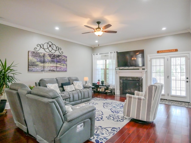 living area featuring dark wood-style floors, a high end fireplace, ornamental molding, and a ceiling fan