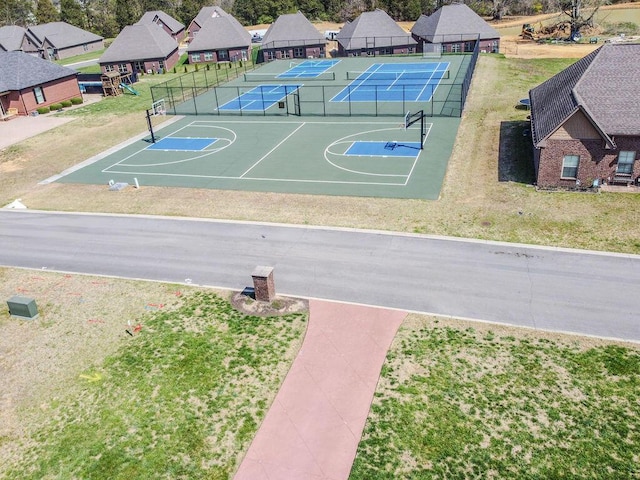 view of sport court featuring a tennis court, fence, and a lawn