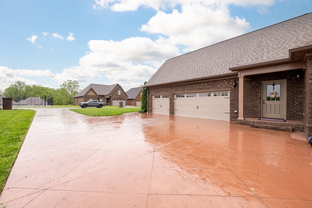 exterior space with a front yard, a shingled roof, brick siding, concrete driveway, and an attached garage