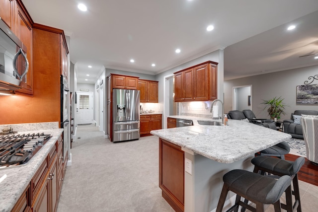 kitchen featuring recessed lighting, a sink, a kitchen bar, a peninsula, and appliances with stainless steel finishes