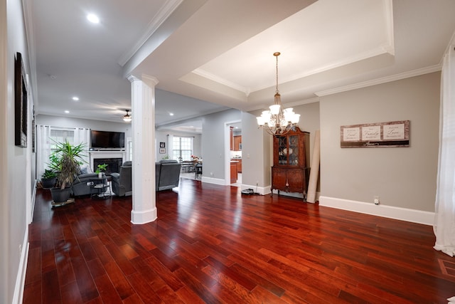 dining space with wood finished floors, ceiling fan with notable chandelier, a fireplace, baseboards, and ornate columns