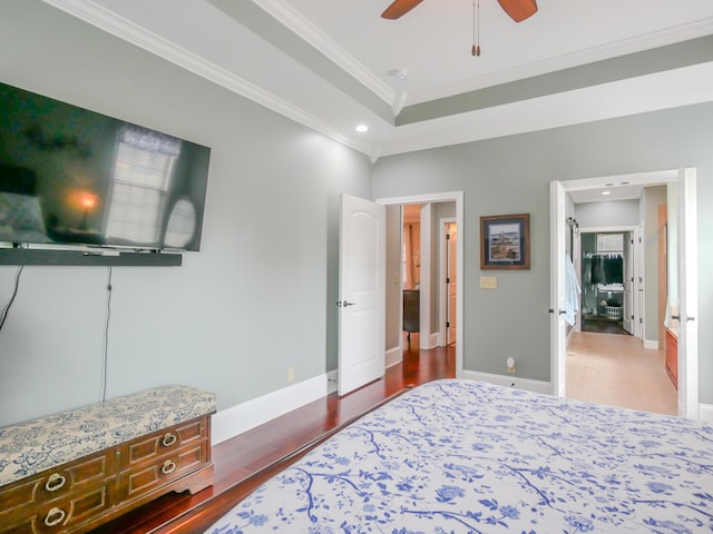 bedroom with a raised ceiling, crown molding, baseboards, and wood finished floors