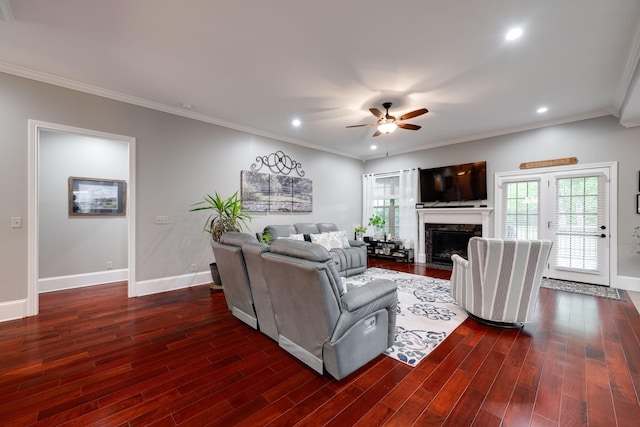 living room featuring baseboards, ornamental molding, ceiling fan, and dark wood-type flooring