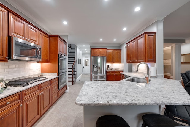 kitchen featuring recessed lighting, a sink, stainless steel appliances, a kitchen bar, and a peninsula