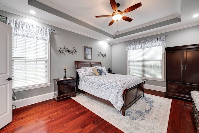 bedroom with dark wood finished floors, ornamental molding, baseboards, a raised ceiling, and a ceiling fan
