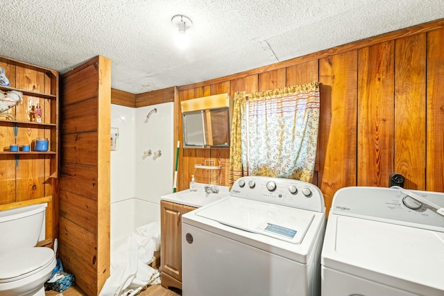 laundry area with a sink, washing machine and dryer, laundry area, and wood walls