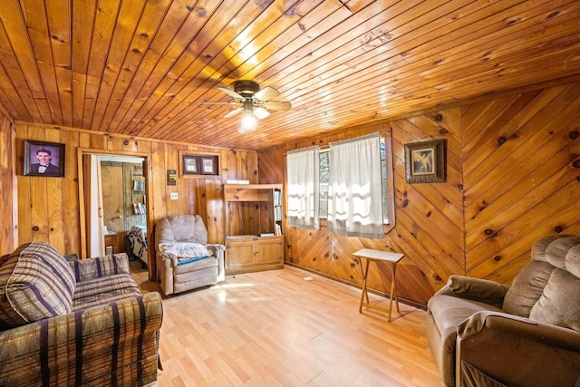 sitting room featuring light wood-style flooring, wood ceiling, wood walls, and ceiling fan