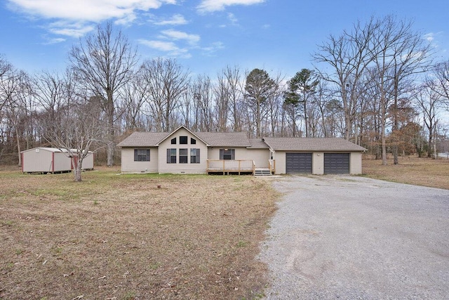 view of front facade featuring a deck, driveway, a front lawn, an outdoor structure, and an attached garage