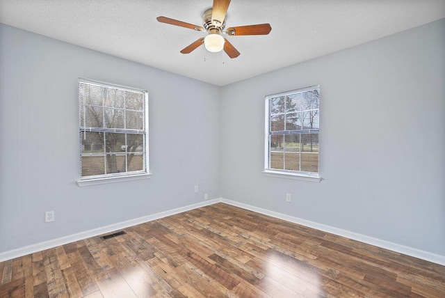 spare room featuring visible vents, baseboards, hardwood / wood-style floors, a textured ceiling, and a ceiling fan