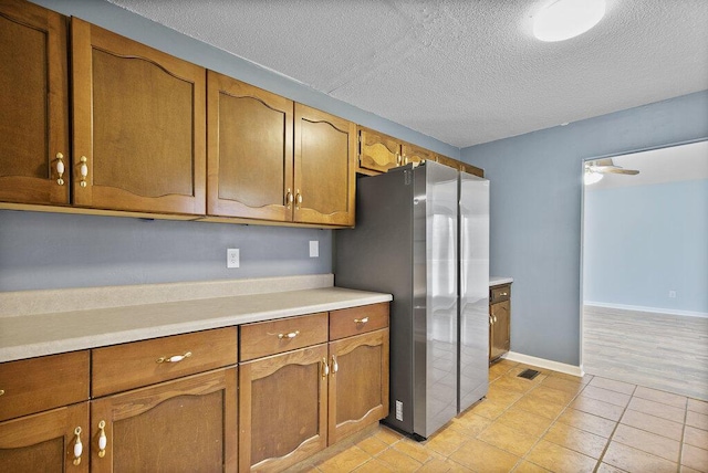 kitchen featuring brown cabinetry, light countertops, and freestanding refrigerator