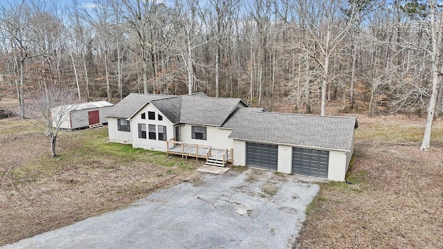 view of front of home with roof with shingles, a wooden deck, a garage, crawl space, and a view of trees