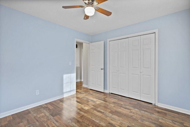 unfurnished bedroom featuring wood finished floors, baseboards, a closet, and ceiling fan