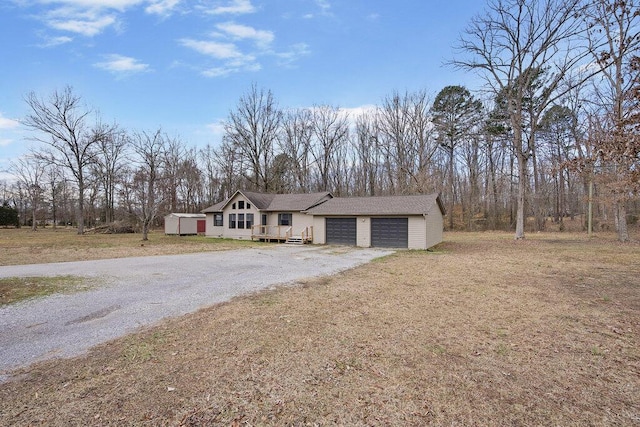 view of front of house featuring an attached garage, gravel driveway, and a front lawn