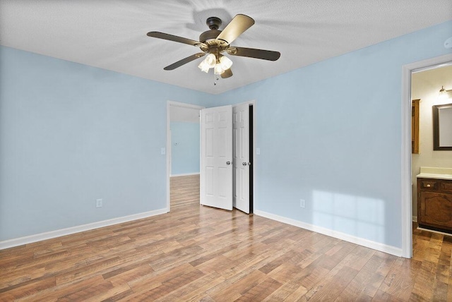 unfurnished bedroom with ensuite bath, a closet, light wood finished floors, baseboards, and ceiling fan