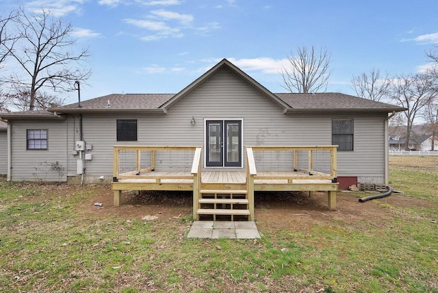 back of property featuring a lawn, a deck, and roof with shingles