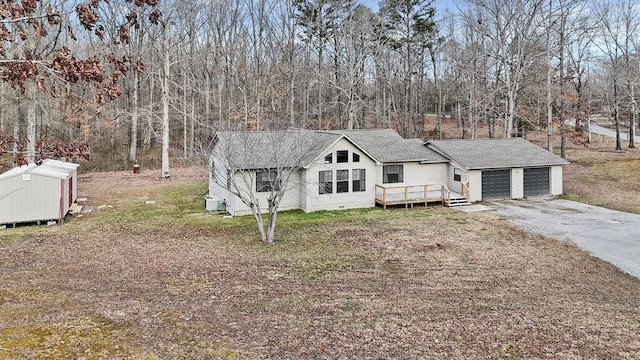 view of front of home featuring aphalt driveway, a wooden deck, an outdoor structure, an attached garage, and crawl space