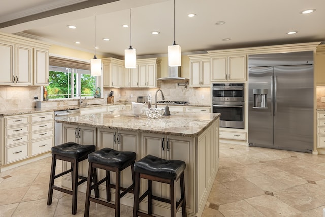 kitchen with light stone countertops, a kitchen breakfast bar, stainless steel appliances, a kitchen island with sink, and cream cabinetry