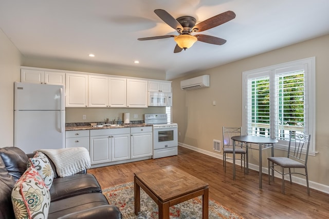 kitchen featuring white appliances, a wall unit AC, sink, white cabinets, and hardwood / wood-style floors