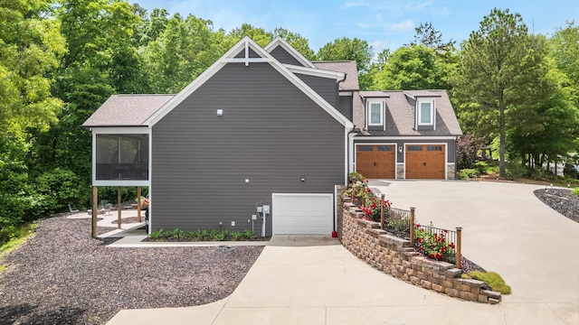 114 Monroe Dr, Ringgold, GA 30736 - view of side of home with concrete driveway, roof with shingles, a sunroom, and view of wooded area