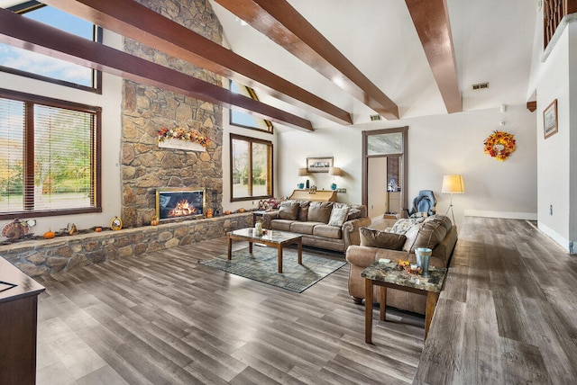 living room with beamed ceiling, a healthy amount of sunlight, dark hardwood / wood-style flooring, and a fireplace