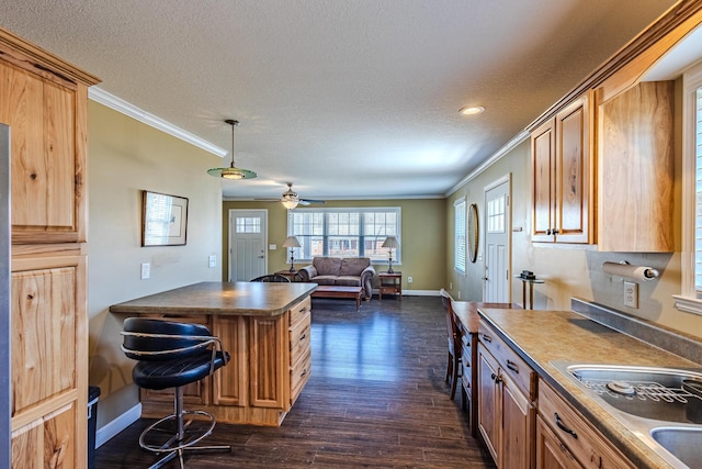 kitchen featuring crown molding, dark wood-type flooring, a textured ceiling, and a kitchen bar