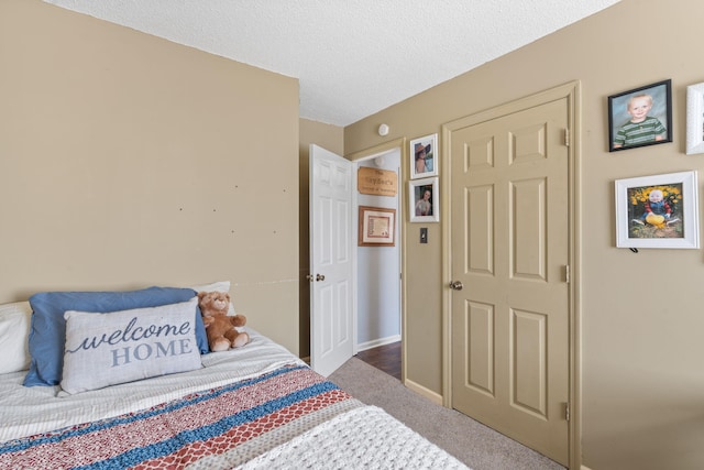 bedroom featuring a textured ceiling, carpet flooring, and baseboards