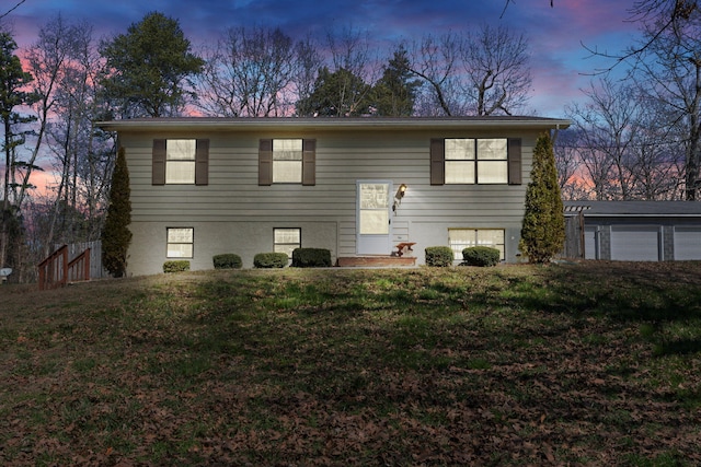 bi-level home with a garage, a lawn, and stucco siding