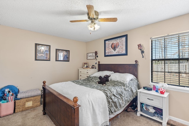 carpeted bedroom featuring a ceiling fan, a textured ceiling, and baseboards