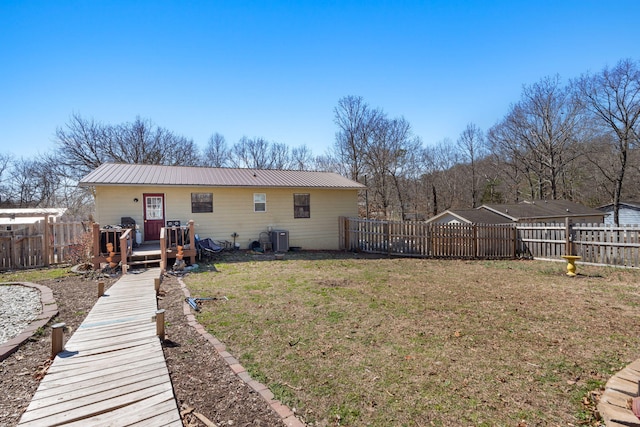 back of property featuring metal roof, fence, a deck, a yard, and central air condition unit