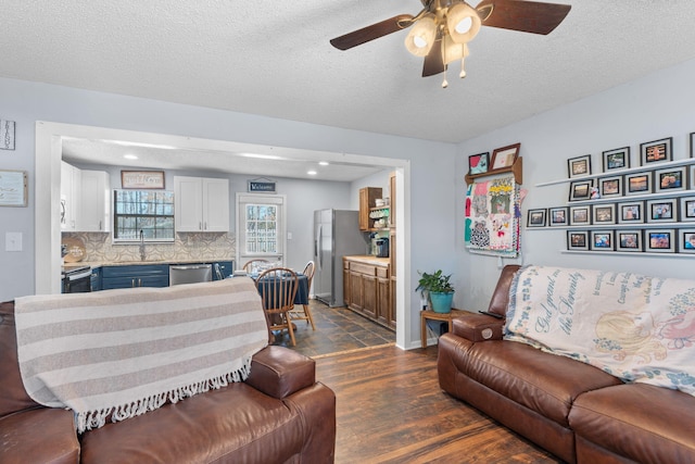 living room featuring a ceiling fan, dark wood finished floors, a textured ceiling, and baseboards