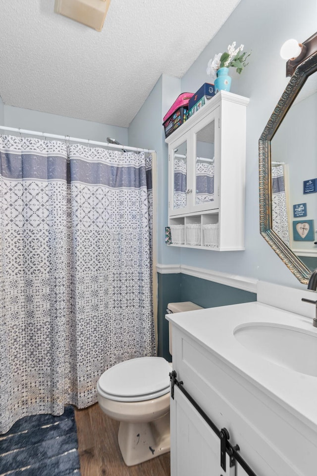 full bathroom featuring a textured ceiling, toilet, a shower with shower curtain, wood finished floors, and vanity