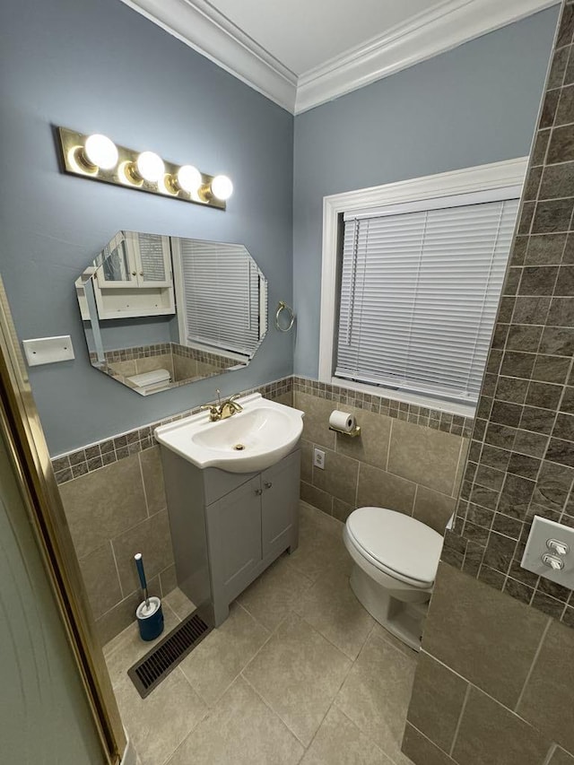 bathroom with visible vents, crown molding, toilet, tile walls, and tile patterned floors