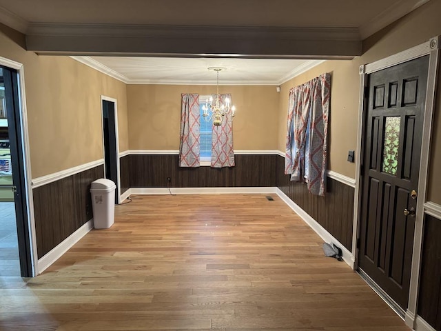 unfurnished dining area with light wood-type flooring, wainscoting, plenty of natural light, and a notable chandelier