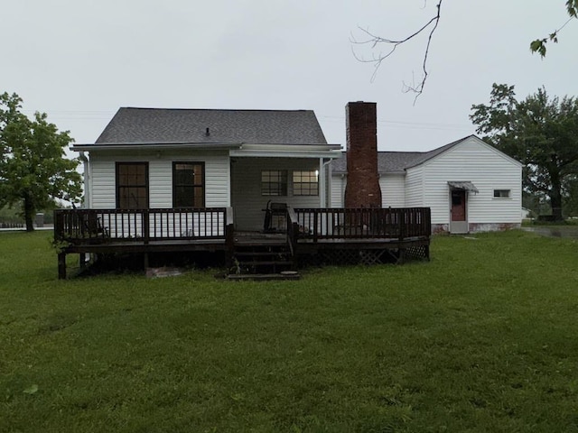 rear view of property featuring a lawn, a chimney, and a deck