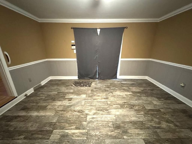spare room with crown molding, wood finished floors, and a wainscoted wall