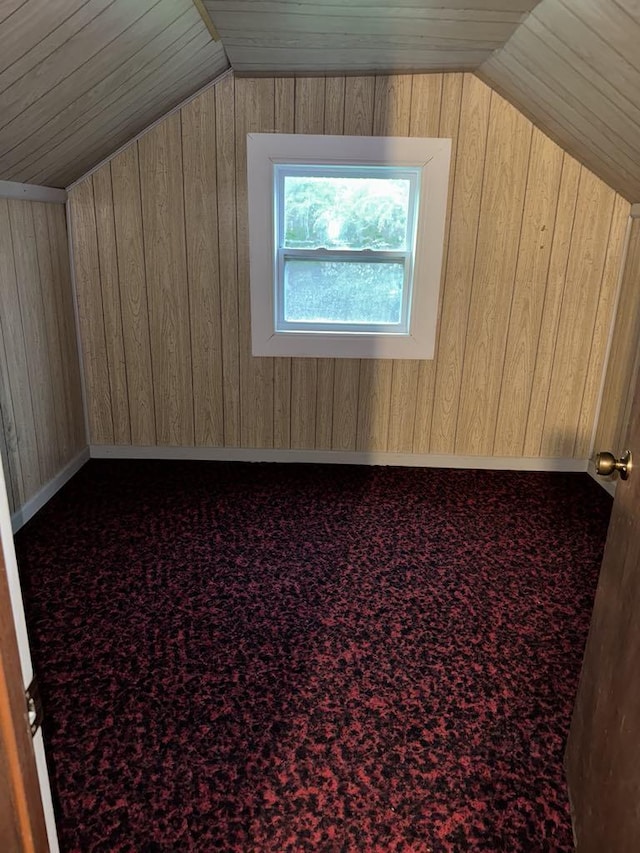 additional living space featuring carpet floors, wood walls, and vaulted ceiling