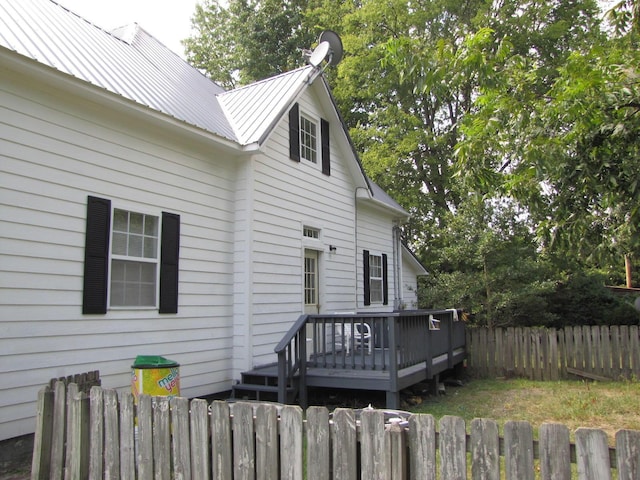 view of home's exterior with a deck, metal roof, and fence private yard