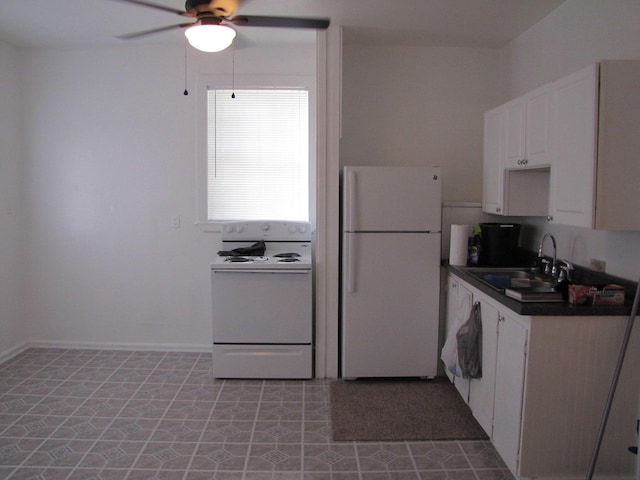 kitchen featuring dark countertops, white cabinets, a sink, ceiling fan, and white appliances