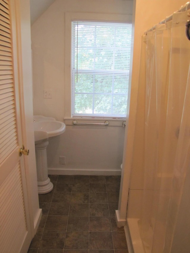 full bath featuring lofted ceiling, curtained shower, baseboards, and tile patterned floors