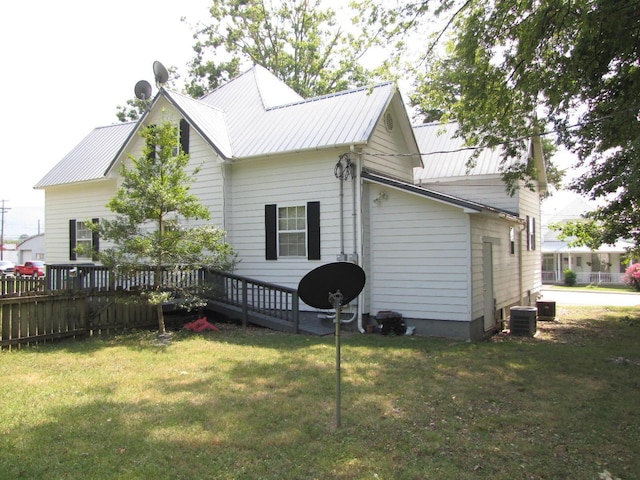 view of side of home featuring cooling unit, metal roof, a yard, and a deck