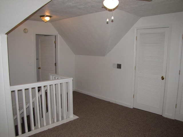 additional living space with carpet floors, lofted ceiling, visible vents, a textured ceiling, and baseboards