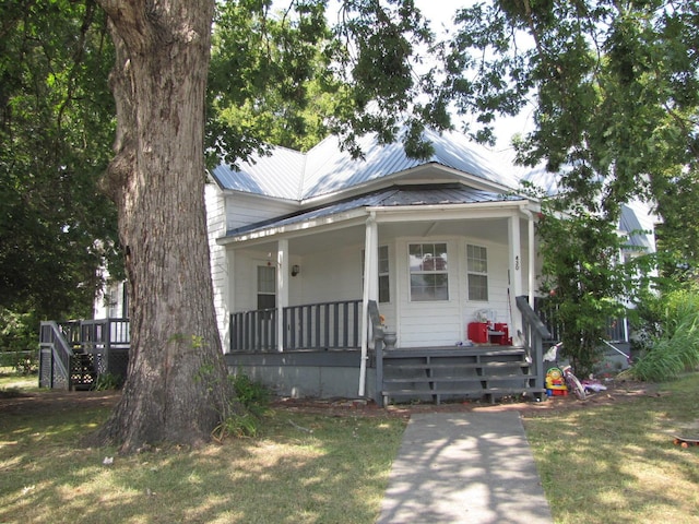 view of front of property with a porch, a front yard, and metal roof