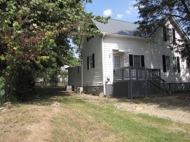 back of house with a yard, metal roof, and central AC unit