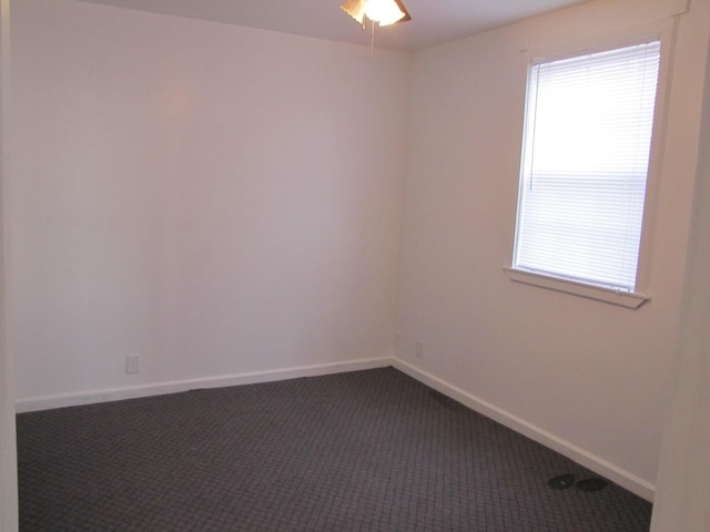 spare room featuring dark carpet and baseboards