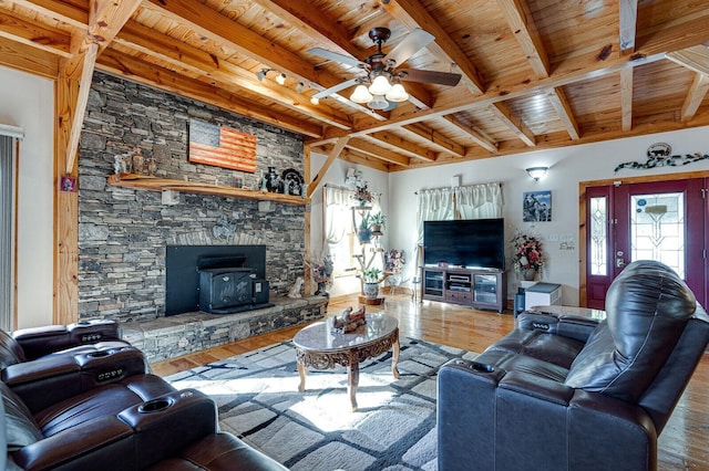living area with ceiling fan, wood finished floors, beam ceiling, a wood stove, and wood ceiling