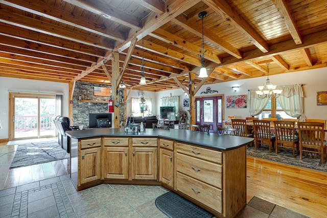 kitchen with an inviting chandelier, plenty of natural light, dark countertops, and a stone fireplace