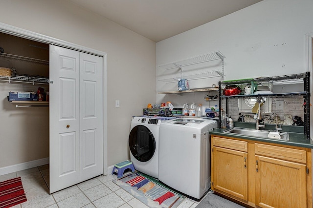 laundry area with washer and clothes dryer, light tile patterned floors, baseboards, a sink, and cabinet space